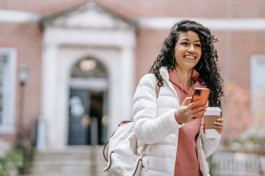 Cheerful student on campus using a phone