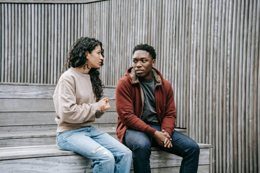 A couple having a serious conversation while sitting on outdoor wooden stairs