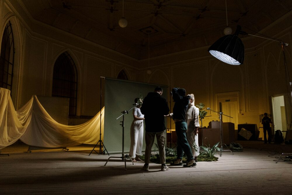 A photography crew setting up lighting and background indoors for a photo shoot