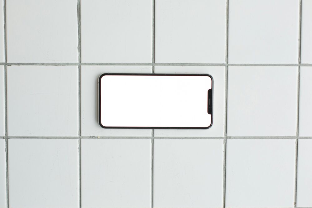 A blank smartphone mockup placed on a clean tiled surface, perfect for showcasing apps or designs.