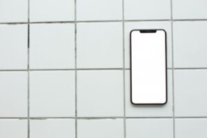 Top-down view of a smartphone with a blank screen on white tiles, ideal for mockup use.
