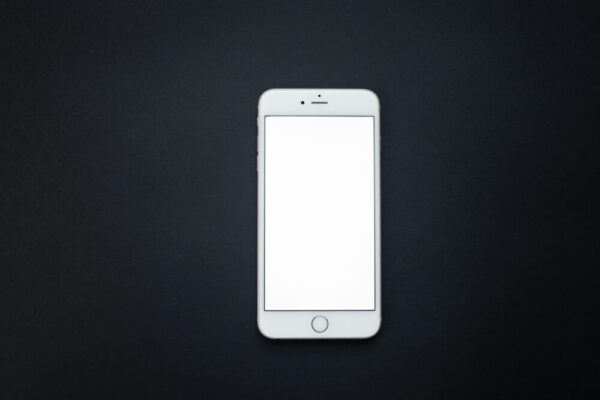 Flat lay of a blank smartphone screen on a dark surface, perfect for mockups and design presentations.
