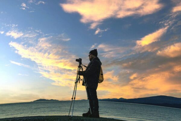 A photographer setting up a tripod on a beach