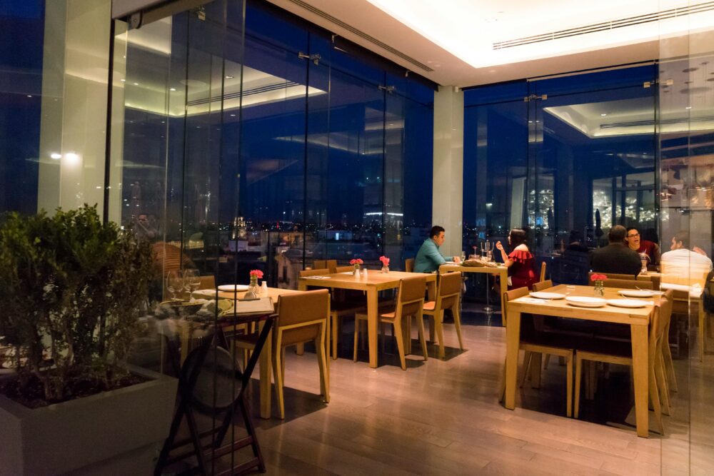Couple enjoying a dinner with city skyline view in a stylish, modern restaurant.
