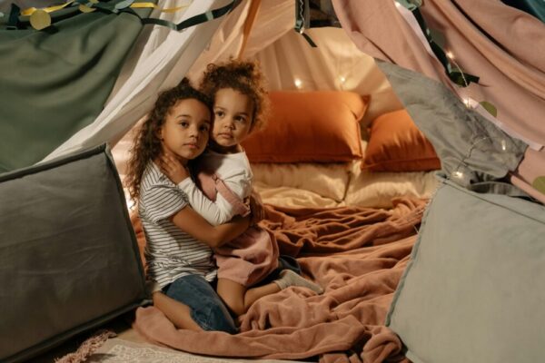 Two young siblings hugging in a cozy indoor tent setting