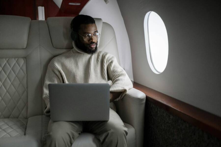 A man wearing headphones uses a laptop in a luxurious airplane cabin