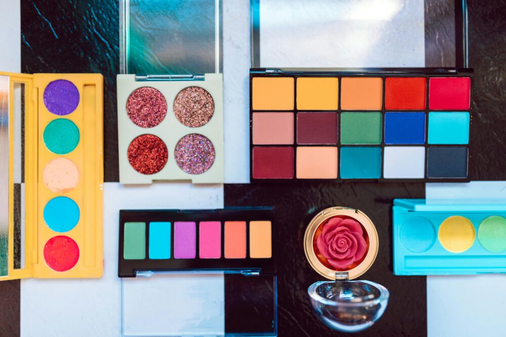 Colorful eyeshadow palettes and makeup accessories displayed in an artistic arrangement.