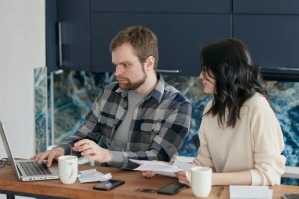 A couple working together on a laptop managing finances at home, showcasing teamwork and concentration.