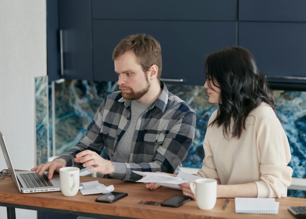 A couple working together on a laptop managing finances at home, showcasing teamwork and concentration.