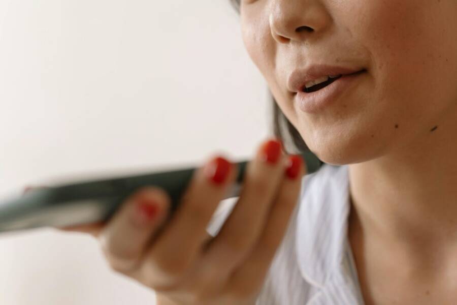 Close-up of a woman using smartphone voice command, showcasing technology and communication