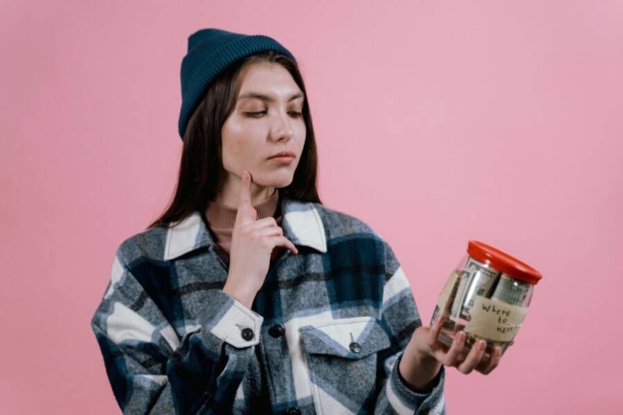 Pensive woman with a savings jar labeled