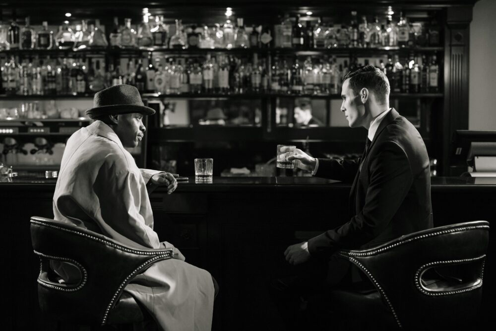 A cinematic, noir-style meeting in a dimly lit bar with a tense atmosphere
