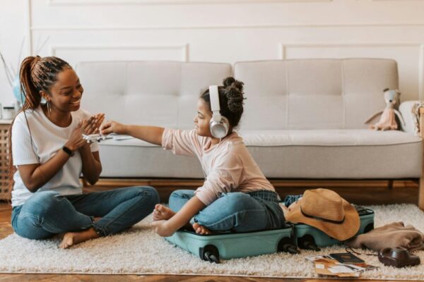 A joyful mother and daughter bond while packing a suitcase, preparing for a fun trip at home