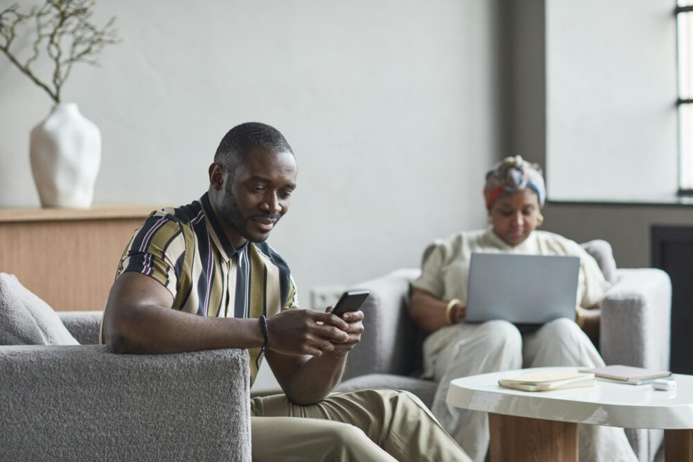 Two colleagues engaging with technology in a contemporary hotel lobby work setting
