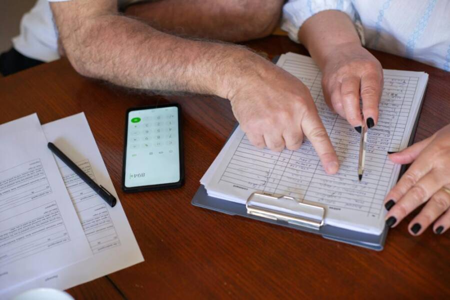 Close-up of hands working on finance planning with documents and a smartphone calculator