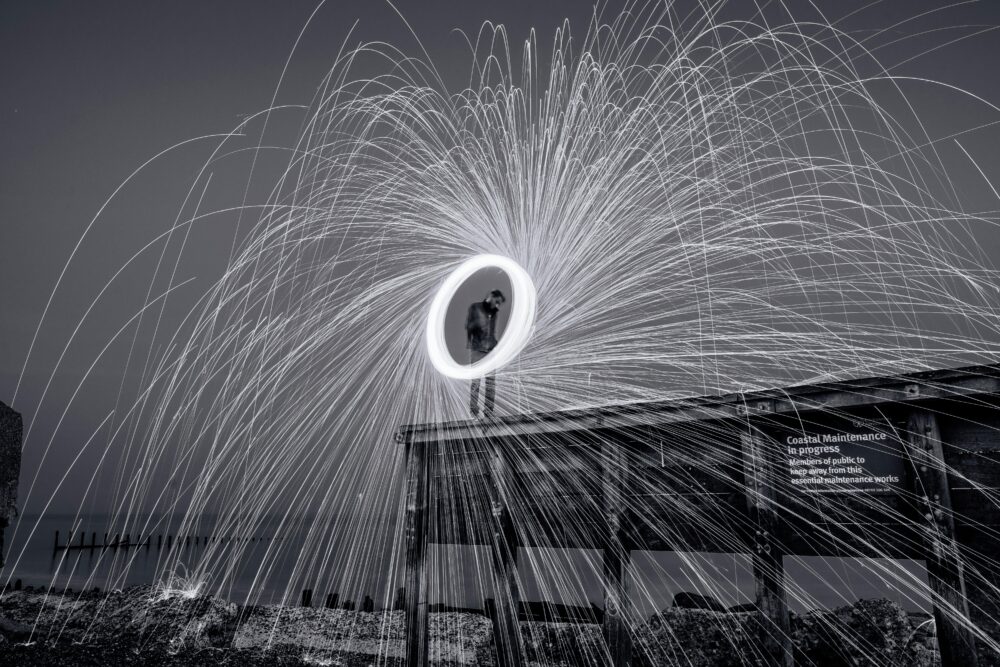 A captivating black and white long exposure photo of a fireworks display at night over a boardwalk