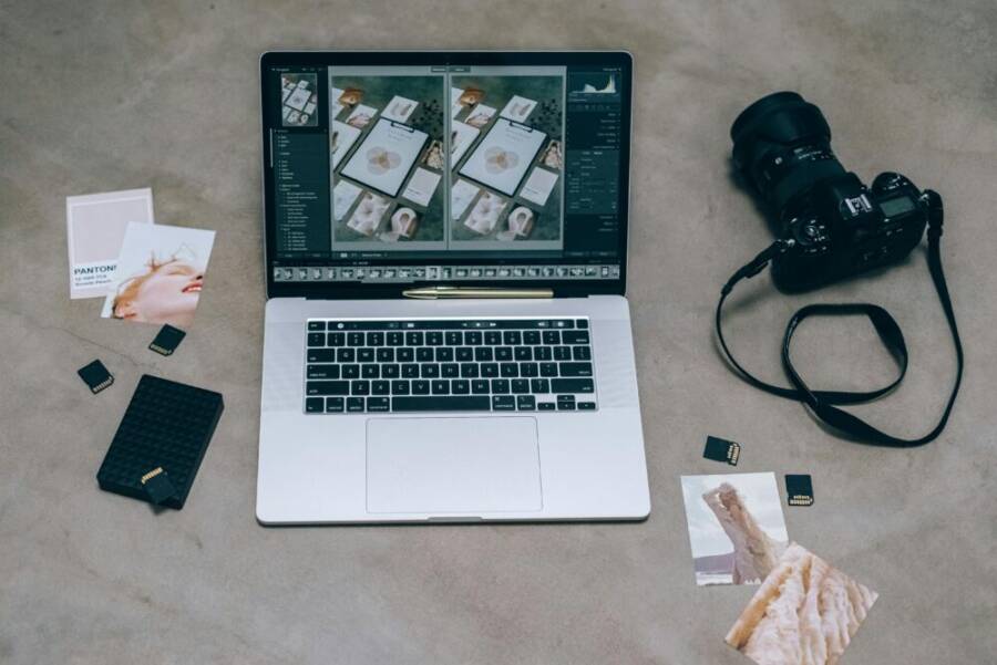 A top view showing a laptop with photo editing software, DSLR camera, and memory cards