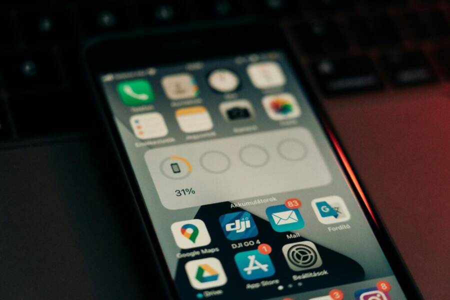 A smartphone with various apps on its screen placed on a keyboard, showing a 31% battery level