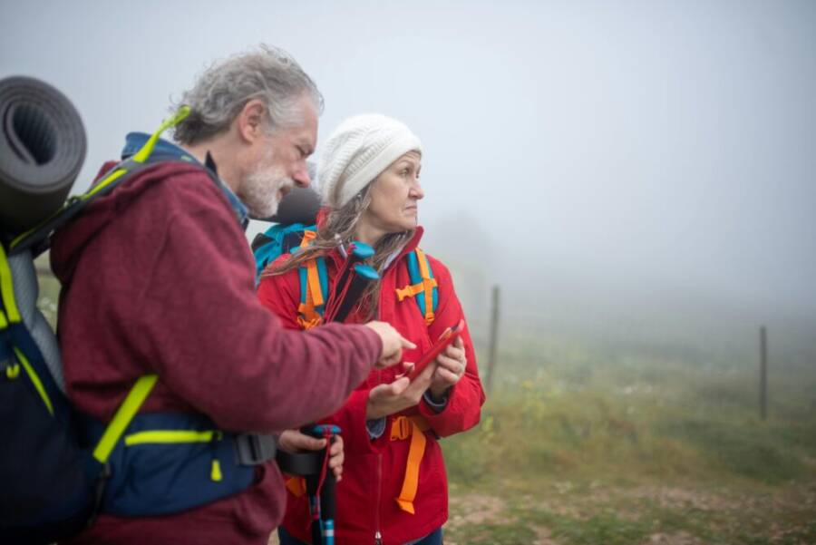 Two hikers consult a smartphone in a foggy rural landscape in Portugal