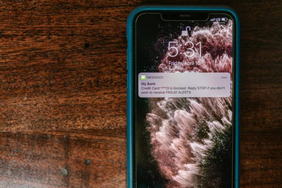 Close-up of smartphone displaying a fraud alert message on wooden surface