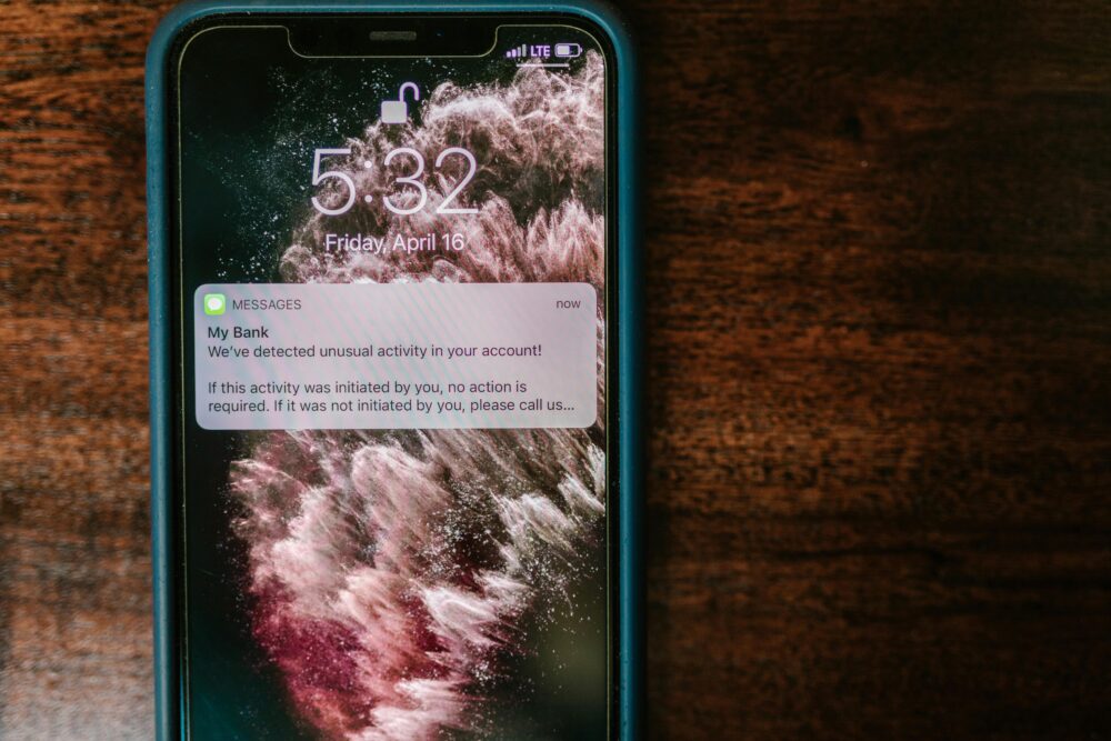 Close-up of a smartphone displaying a bank alert notification on a wooden table