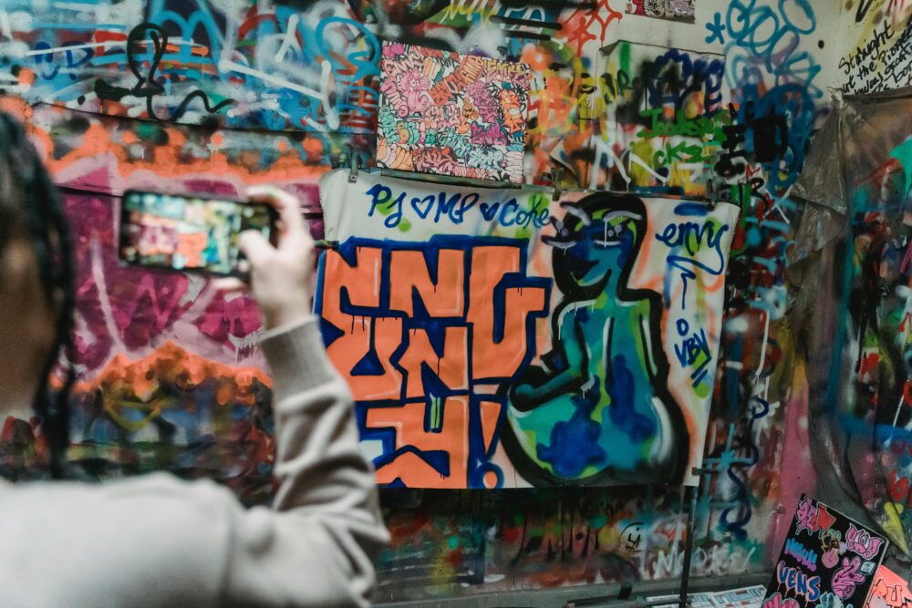Capturing colorful graffiti art on a wall with a smartphone, showcasing urban creativity.