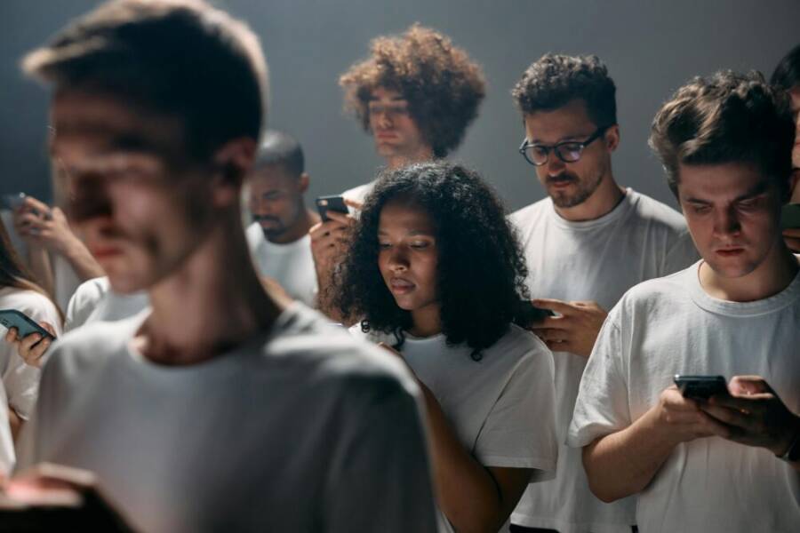 Diverse group of adults engrossed in smartphones, emphasizing tech-driven social isolation