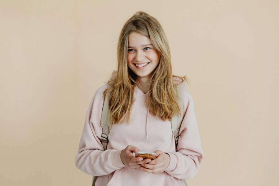 A cheerful teenager with a smartphone indoors