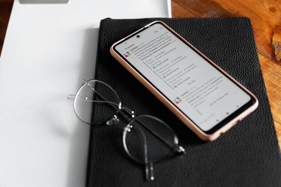 image of a smartphone on a desk with a notebook and eyeglasses