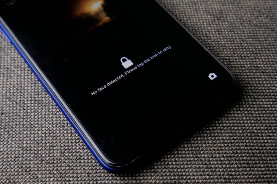 Mobile phone with no face detected message on lock screen on a textured fabric surface