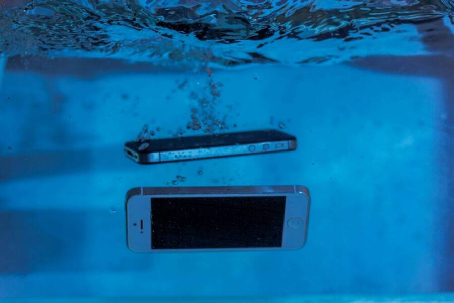 Two smartphones immersed underwater with bubbles, showcasing water-resistant test perspectives