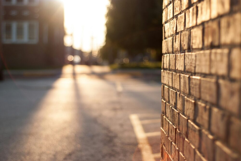 Close-up of a sunlit brick wall with blurred urban street in the background at sunset