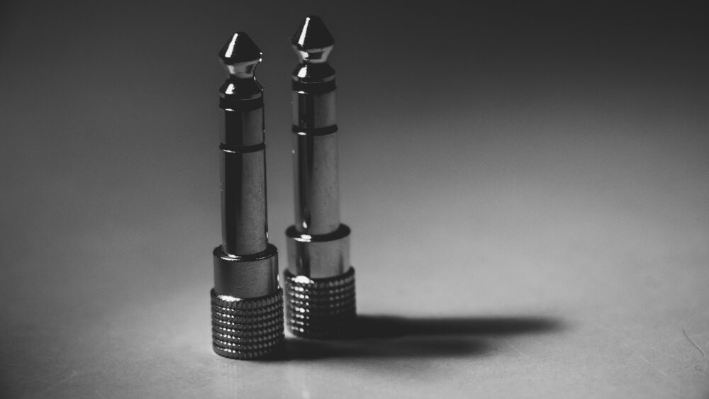 Black and white close-up of metallic audio jack connectors on a flat surface
