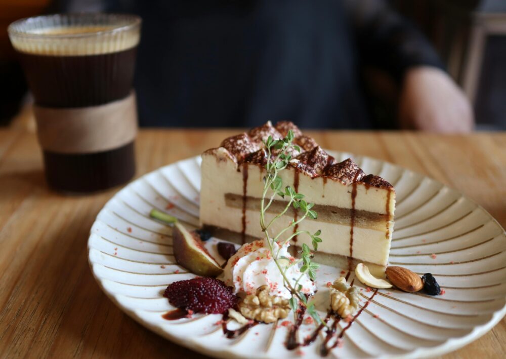 Close-up of tiramisu with nuts and coffee on a wooden table, creating a delicious culinary setting