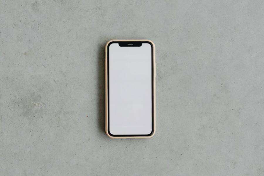 Top view of a modern smartphone with a blank white screen on a gray concrete background, ideal for mockups.