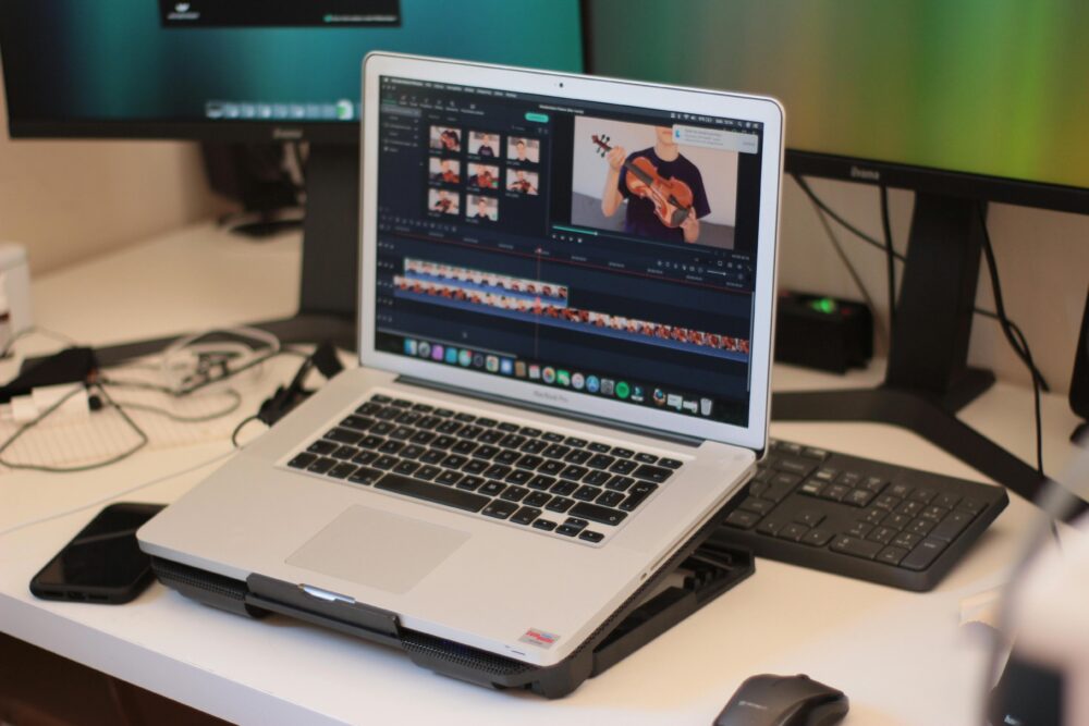 A workspace featuring a laptop editing a video, showcasing modern technology and video editing software