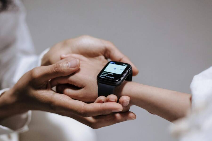 Close-up of an adult helping a child with a smartwatch, showcasing modern technology and parental guidance