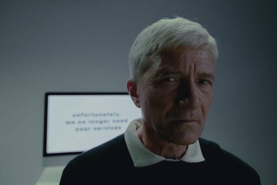 Elderly man looking thoughtful after reading a termination notification on screen