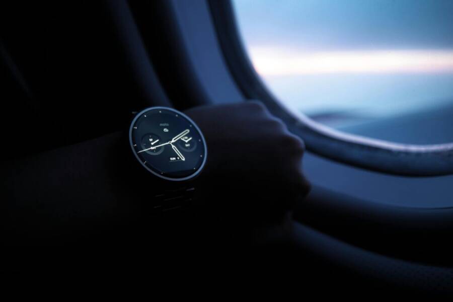 A smartwatch on a wrist shown against an airplane window view during flight