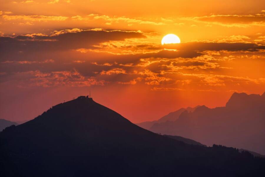 令人驚嘆的日落，明亮的橙色天空在山​​​​脈上投下陰影。