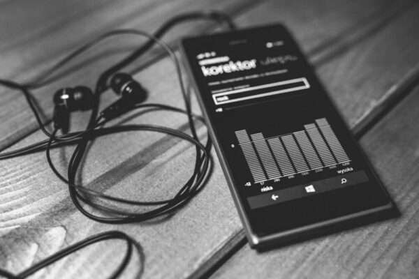 Monochrome photo of a smartphone with earphones and audio equalizer on screen.