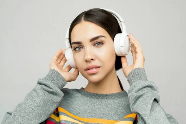 黃色白色拿著耳機灰色和毛衣的女人