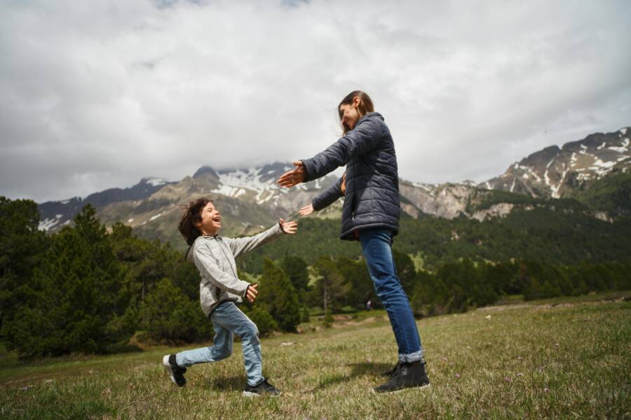 女人和孩子在山附近的綠草地上玩耍