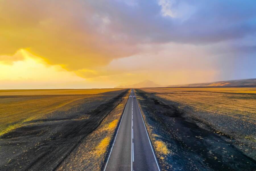 在絢麗的金色日出中，從空中俯瞰天際一條空曠的公路，景色令人嘆為觀止。