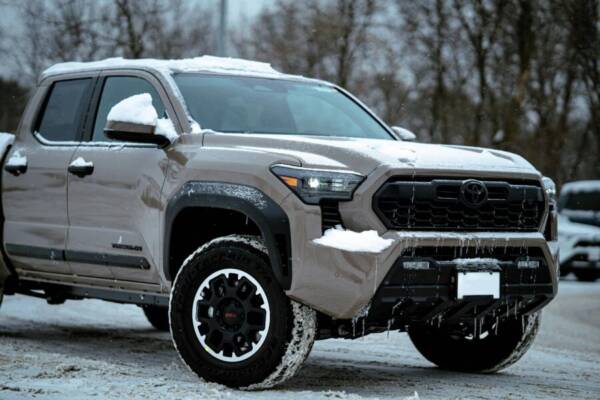 一輛堅固耐用的越野卡車在冬天停在積雪覆蓋的地面上。