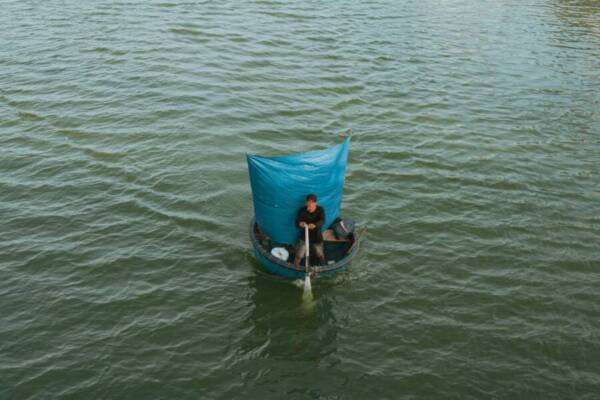 一名漁民在越南平順省海域駕駛著一棵掛著藍色船隻的傳統船隻。