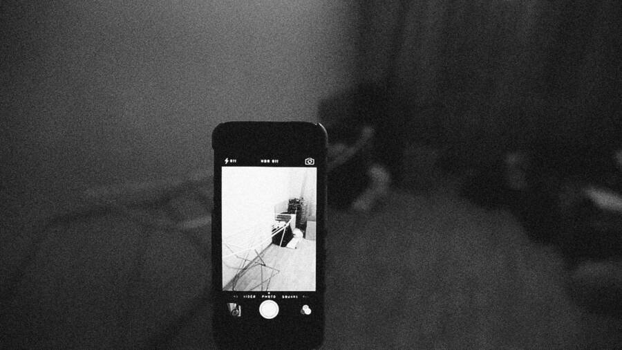 Artistic grainy black and white image of a smartphone capturing a room scene