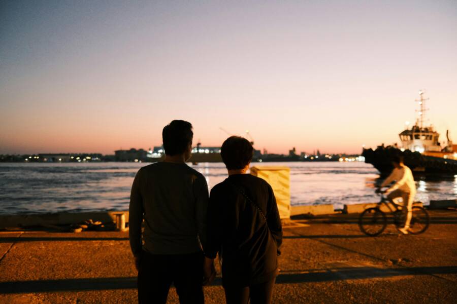 A couple stands by Kaohsiung Harbor at sunset, enjoying the serene view