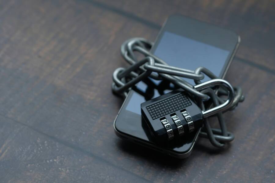How to Fix the Connection Not Private Error on Your Phone Close-up of a smartphone wrapped in a chain with a padlock, symbolizing strong security.