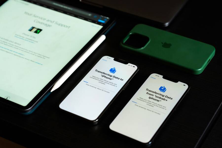 High-angle view of digital devices including iPhones and an iPad on a desk, showcasing data transfer